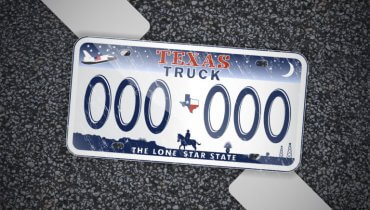 Placa de auto con el nombre en inglés de Texas Truck sobre un fonde de asfalto