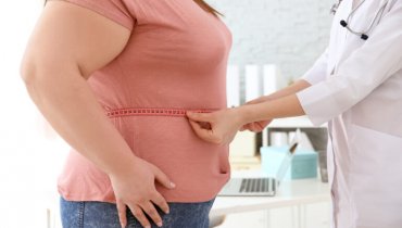 Doctora midiendo con un metro la cintura de una paciente obesa para su seguro médico