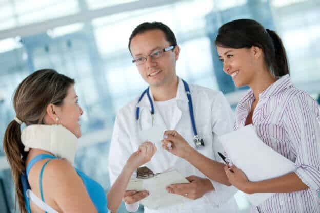 Mujer con cuello ortopédico conversando con doctor y una asesora para inscribirse y comprar seguro médico