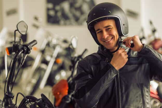 Hombre de chaqueta sonriendo con casco puesto pensando si conviene comprar una moto usada