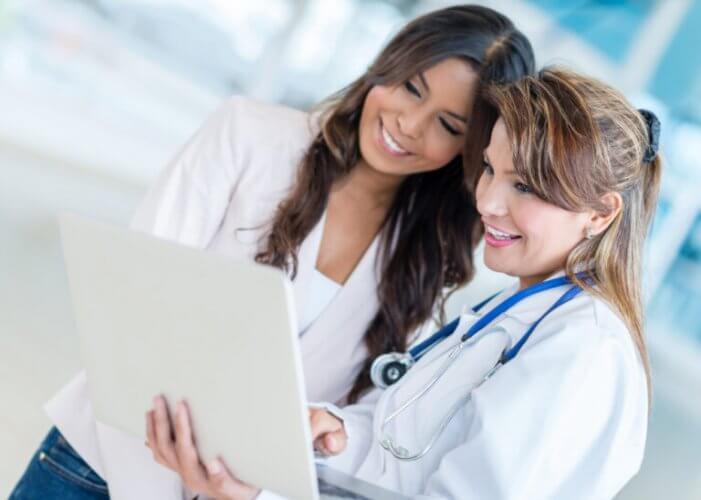 Mujer médico y chica revisando el obamacare 2021 seguro en una laptop blanca
