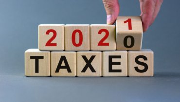 Mano de un hombre sosteniendo un cubo de un grupo de cubos que dice 2021 TAXES