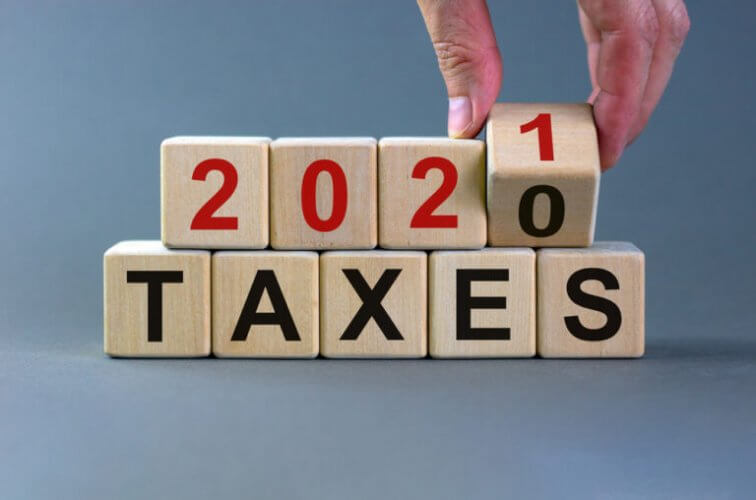 Mano de un hombre sosteniendo un cubo de un grupo de cubos que dice 2021 TAXES