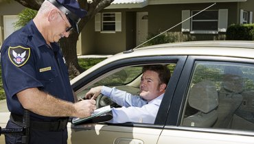 Hombre dentro de un auto detenido por un policía que le pide su seguro de auto