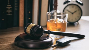 Mazo de juez indicando un caso de DUI con una llave y vaso de licor en escritorio