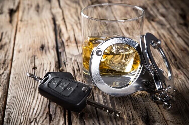 Llaves de auto y esposas métalicas sobre un vaso de licor de quien cometió un DUI en California