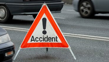 Señal triangular roja con el nombre en inglés Accident en la mitad de la carretera con autos
