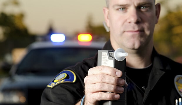 Policía rudo sosteniendo un alcoholímetro diciendo las consecuencias de un DUI en California