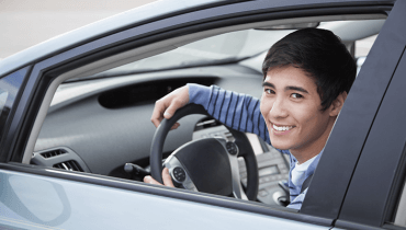 Hombre joven feliz por tener un carro con el seguro mas barato de estados unidos