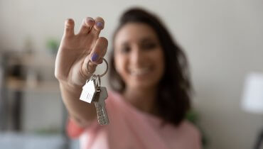 Mujer joven sonriendo y sosteniendo de las manos sus nuevas llaves al rentar casa