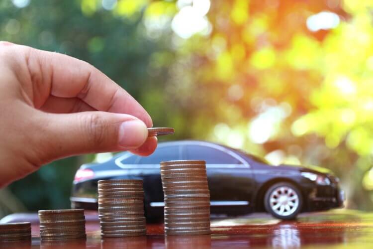 Mano de hombre contando varias pilas de monedas para encontrar un seguro de auto barato