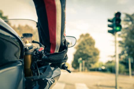 Mano de hombre sujetando el acelerador de una moto que no necesita licencia frente al semáforo