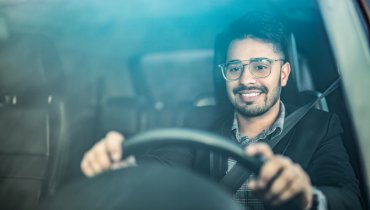 Hombre de lentes al volante de su auto conduciendo sin saber que es el liability