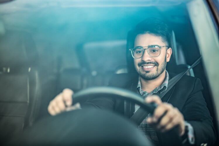 Hombre de lentes al volante de su auto conduciendo sin saber que es el liability