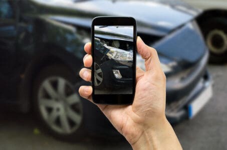 Mano tomando una foto a un automóvil que chocó contra conductor sin seguro