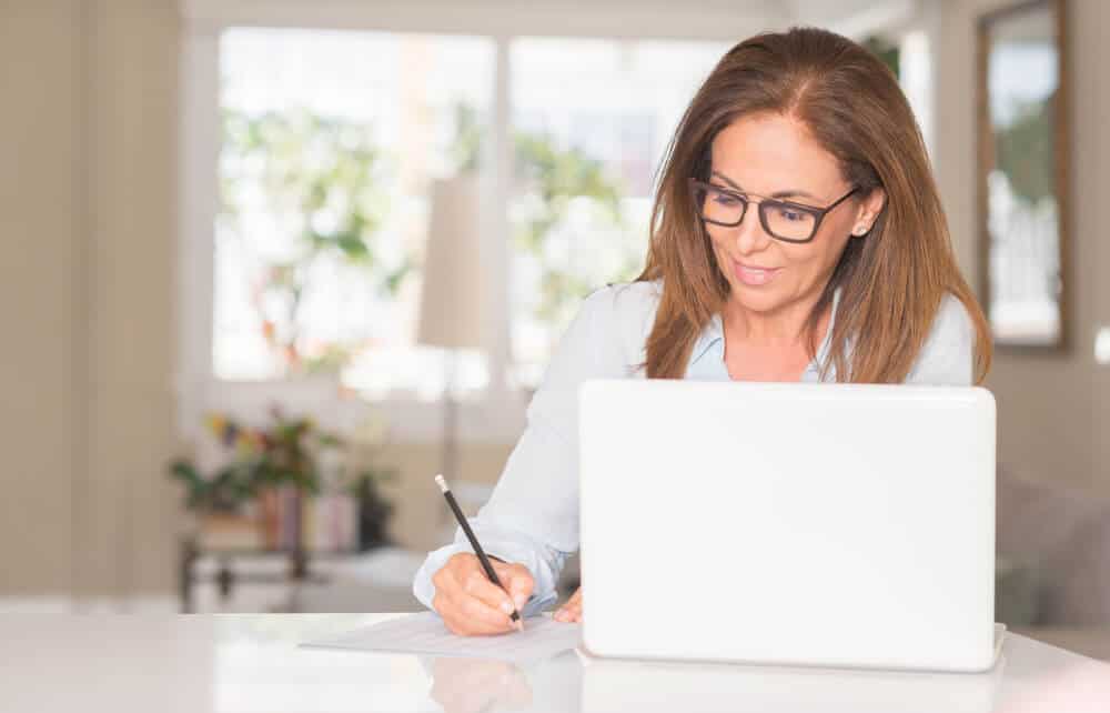 mujer hispana tomando notas y buscando seguro de auto en estados unidos con laptop