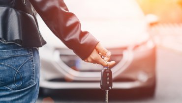 mano sosteniendo llaves con auto de fondo con seguro y franquicia