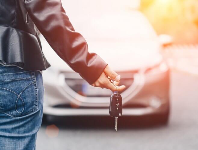 mano sosteniendo llaves con auto de fondo con seguro y franquicia