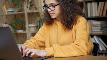 mujer hispana joven en computadora buscando como funciona el seguro de auto