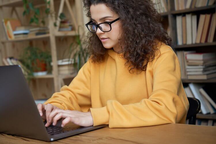 mujer hispana joven en computadora buscando como funciona el seguro de auto