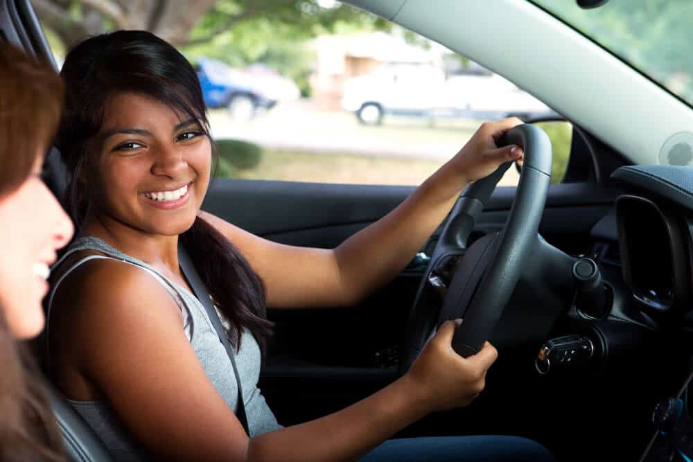 joven sonriendo manejando un auto con amiga