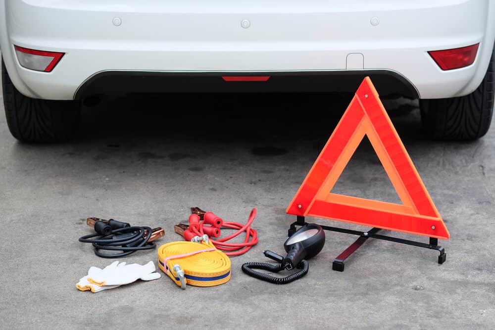 accesorios de un kit de emergencia en el suelo frente a un auto