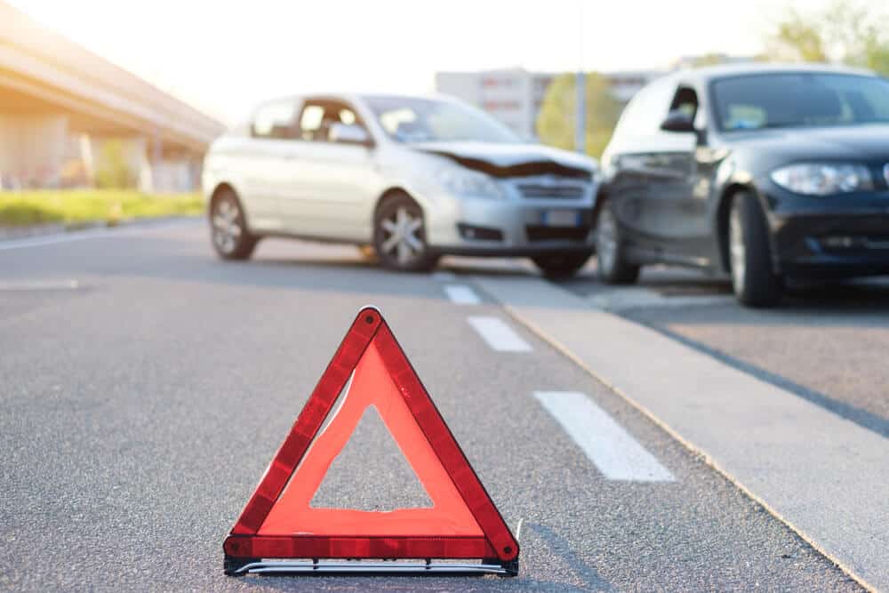 triangulo de señalamiento de trafico en carretera con accidente automovilistico de fondo