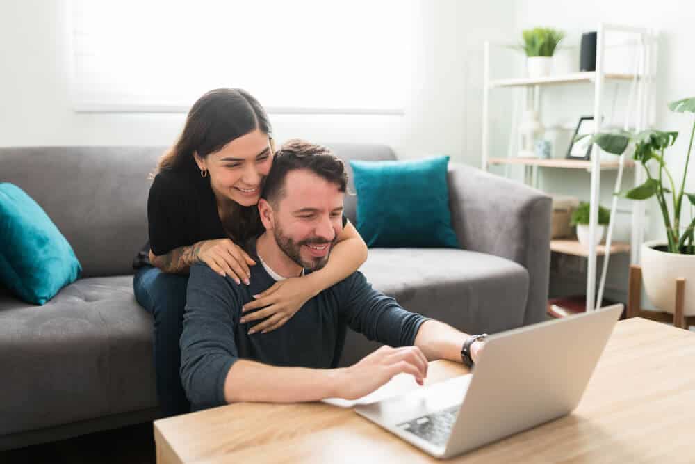 pareja feliz en su sala buscando seguro gap en laptop