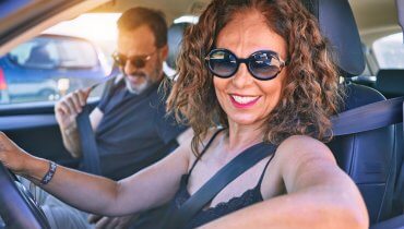 pareja hispana sonriendo en auto porque ahorran en su aseguranza de carro