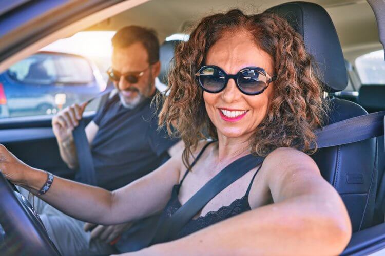 pareja hispana sonriendo en auto porque ahorran en su aseguranza de carro