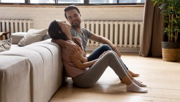 Pareja joven sonriendo en su sala sobre el piso