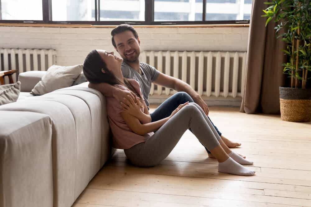 Pareja joven sonriendo en su sala sobre el piso