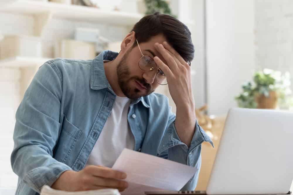 Hombre con lentes frustrado leyendo un historial crediticio