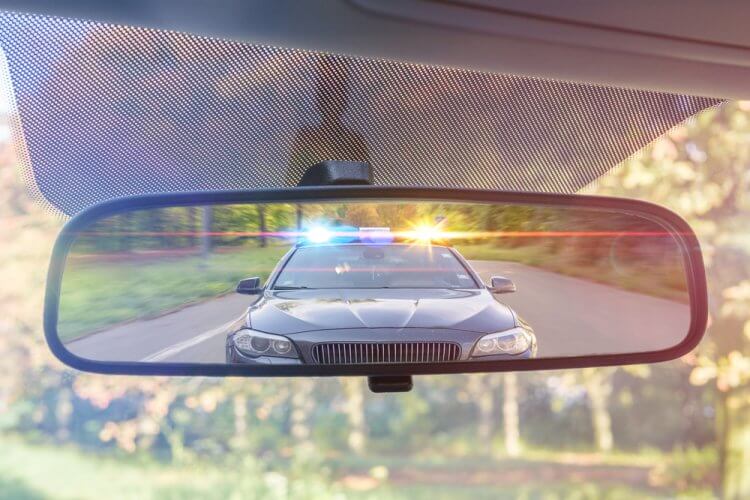 Espejo retrovisor de un auto que muestra las luces de una patrulla