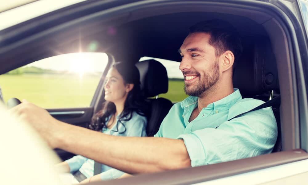 Pareja joven hispana sonriendo mientras estan paseando en su auto