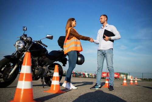 chica joven dandole la mano al profesor de manejo de motocicleta al pasar su examan