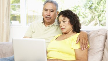 Hombre y mujer mayores en un sillon viendo la computadora portatil