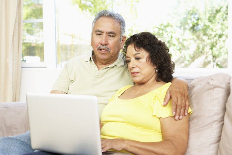 Hombre y mujer mayores en un sillon viendo la computadora portatil