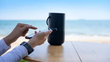 Persona usando celular con playa de fondo.