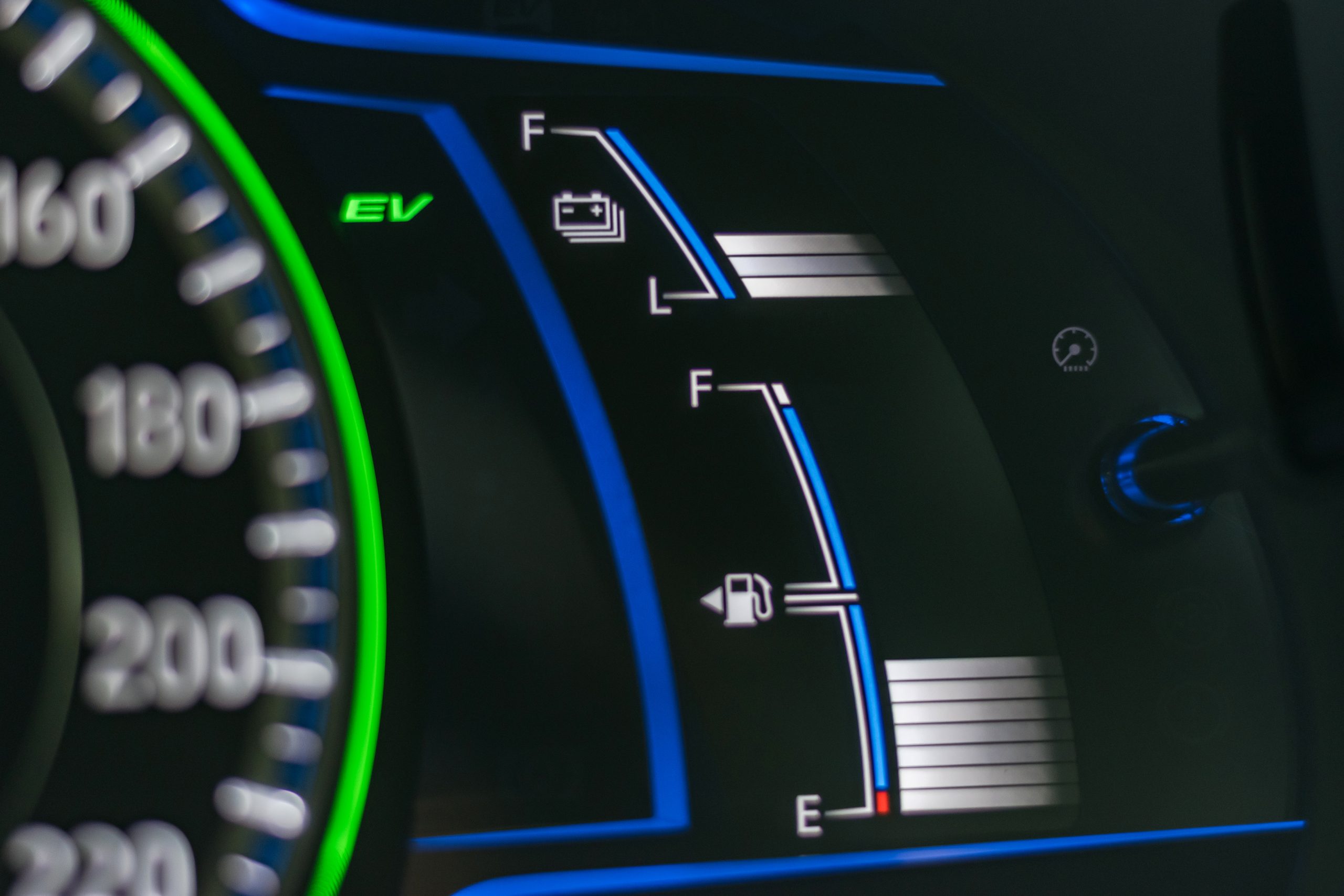 Panel de instrumentos de un automóvil híbrido mostrando indicador EV, nivel de batería y medidor de combustible, representando eficiencia energética y tecnología híbrida.