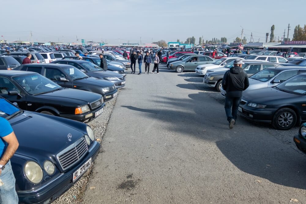 Lote de autos usados con compradores revisando vehículos, una escena común al evaluar opciones relacionadas con títulos salvage.