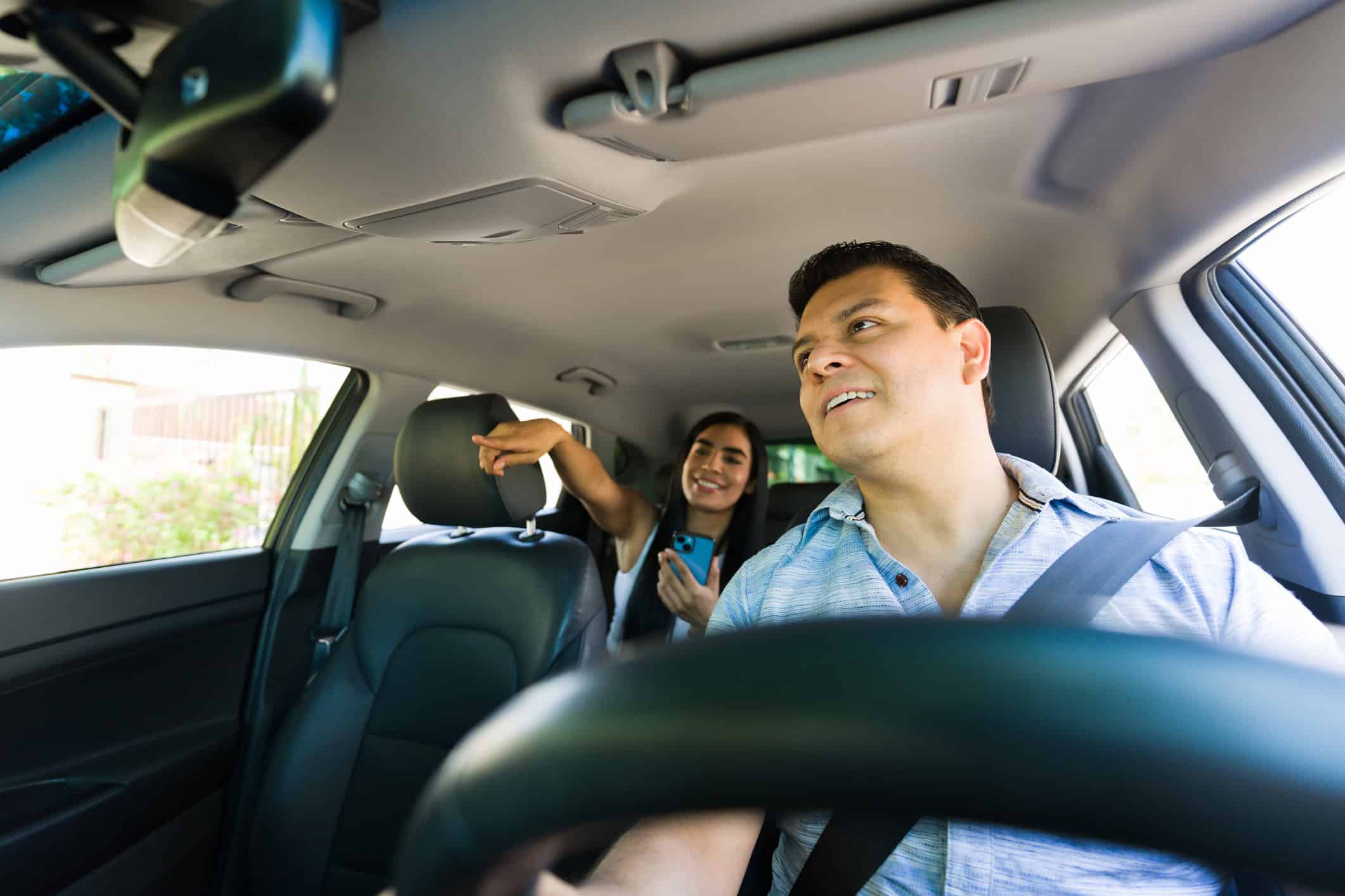 Conductor de Uber llevando a una pasajera mientras trabaja en un viaje solicitado a través de una app de transporte compartido.