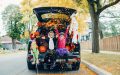 Niño y niña sentados en la parte trasera de un auto, lanzando flores de día de muertos y celebrando que sus papás aprendieron consejos de seguridad para conductores en Halloween