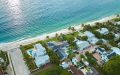 Vista aérea de un vecindario residencial en la costa de Florida, con casas cercanas a la playa, palmeras y el océano de aguas turquesas al fondo.
