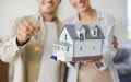 Pareja mostrando llaves y maqueta de vivienda, relacionada con qué no cubre el seguro de casa al comprar un nuevo hogar