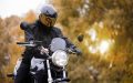 Un motociclista con casco y equipo de protección conduce su moto al aire libre, representando los tipos de cobertura para motocicleta en seguros y la importancia de ir protegido