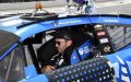 Daniel Suarez, piloto ajusta su equipo dentro del auto antes de competir, reflejando cómo se prepara un piloto de NASCAR