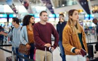 Viajeros en aeropuerto esperando turno, reflejando requisitos al viajar con residencia americana en vuelos internacionales.