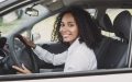 Conductora al volante de su vehículo ante los gastos ocultos de tener un auto en USA