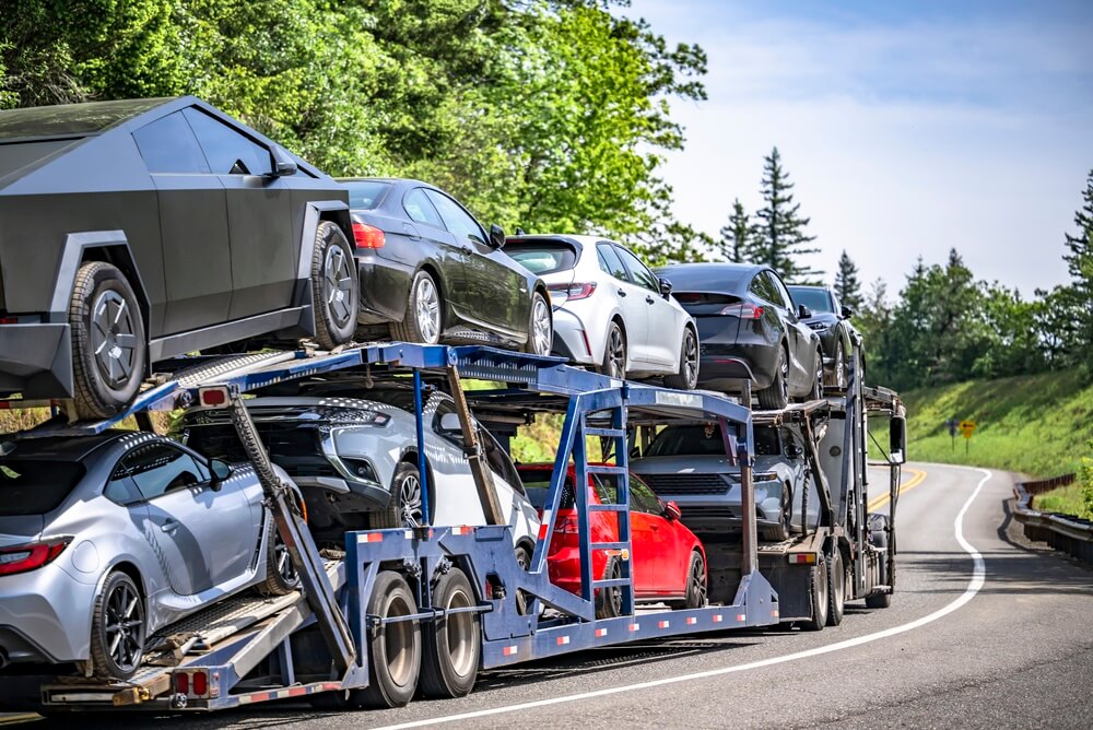 Camión transportador llevando varios autos por carretera, una opción común para transportar auto de un estado a otro en Estados Unidos.